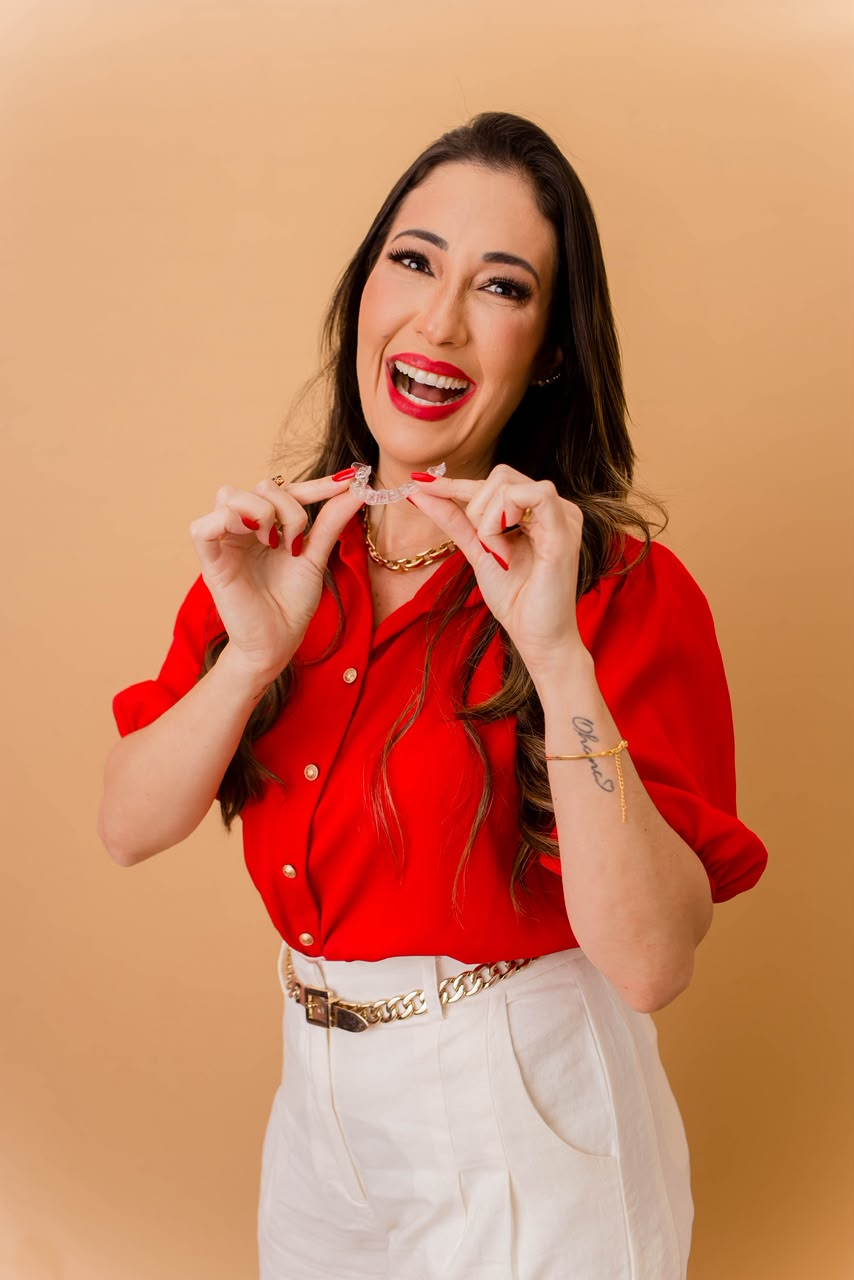 Dra. Jamille Lima sorrindo e segurando um alinhador